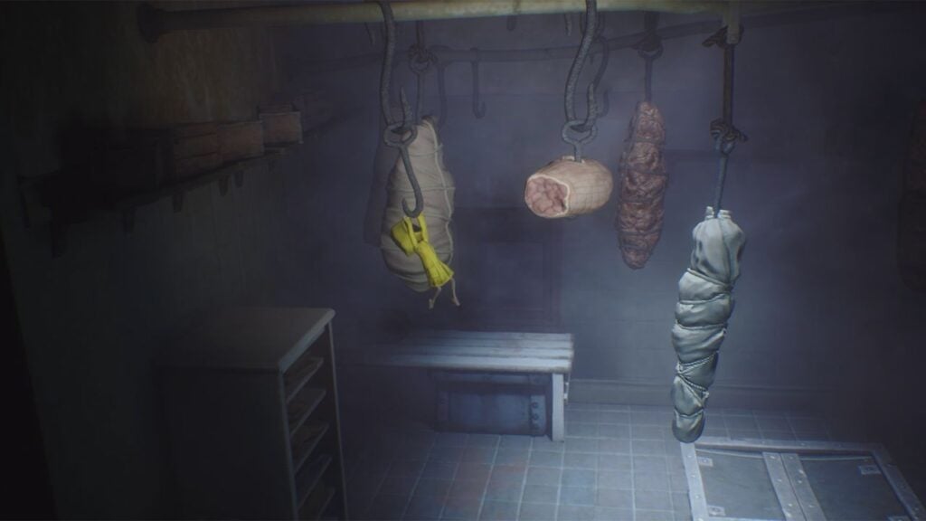  It shows a screen from Little Nightmares, with the player character, a girl in a yellow coat, swinging using a meat hook in a gloomy meat locker.
