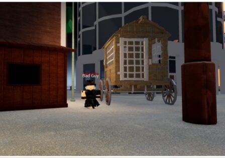 The image shows a bandit next to a wheeled shack in between two buildings at night time. There is a faint glow coming from the buildings lights either side and the bandit is wearing all black and looking to the viewer